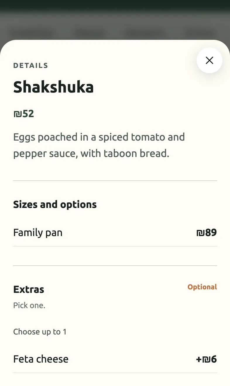 An item detail sheet on a phone: shakshuka with a family-pan size and an optional feta extra.